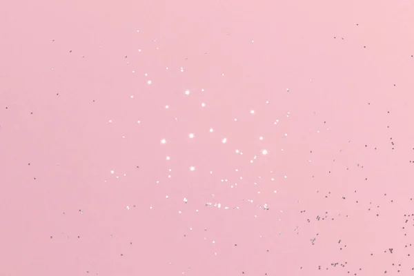 Sparkling silver glitter on pink background. Holiday blurred lights