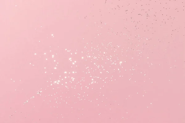 Sparkling silver glitter on pink background. Holiday blurred lights