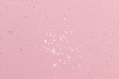 Pembe arka planda parıldayan gümüş parıltı. Tatil ışıkları bulanıklaştı