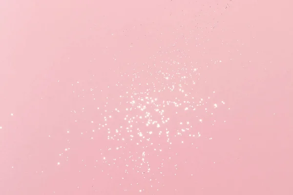 Sparkling silver glitter on pink background. Holiday blurred lights