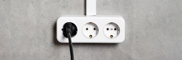 Group of white european electrical outlets with plug on gray concrete wall banner. Wide panoramic header