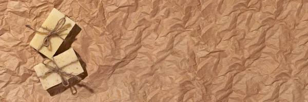 Natural handmade soaps on brown crumpled, wrinkled recycle craft paper background, top view banner. Zero waste, eco friendly vegan soap bars. Wide panoramic header