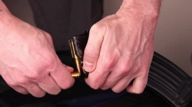 Erkek eli Kalaşnikov 'un saldırı tüfeği şarjörünü fişeklerle boşaltıyor. Ateşleme şarjörü 7.62 kalibre, AK 47 yakın çekim için.
