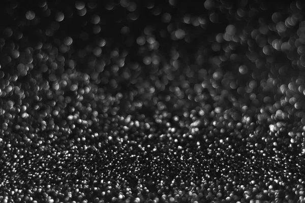 Gray black sparkling glitter bokeh background, christmas abstract defocused texture. Holiday lights. Snowy shiny sparkle stars for celebrate