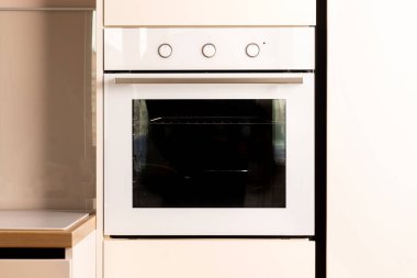 Modern bright white and beige kitchen with built-in oven closeup
