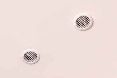 Beyaz plastik ızgaralı, bej tavanlı, yuvarlak havalandırma.