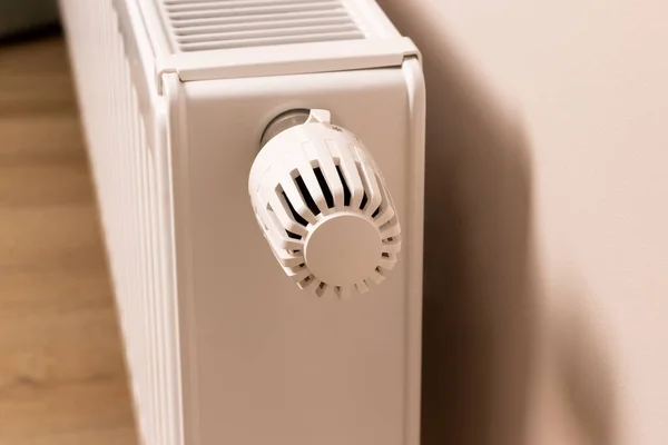Control valve of home heating radiator in modern living room. Temperature regulator. Low temperature reduces heating costs