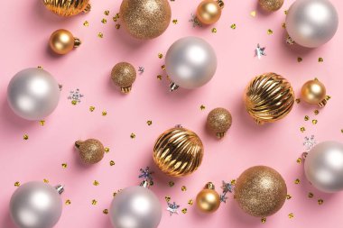 Üzerinde altın ve gümüş toplar ve pembe arka planda konfeti olan Noel kartı