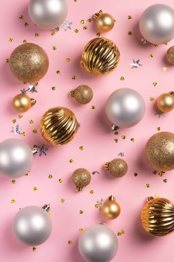 Üzerinde altın ve gümüş toplar ve pembe arka planda konfeti olan Noel kartı
