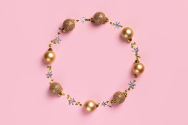 Altın Noel topları ve pembe arka planda parıltılı konfeti kalplerinden oluşan bir çerçeve.