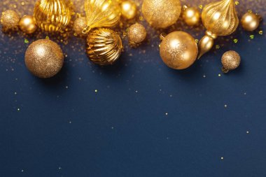 Altın parıltılı toplarla Noel afişi ve mavi arka planda fotokopi alanı olan oyuncaklar