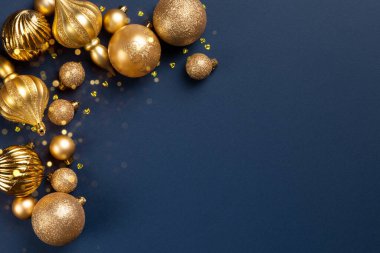 Altın parıltılı topları olan Noel çerçevesi ve mavi arka planda fotokopi alanı olan oyuncaklar