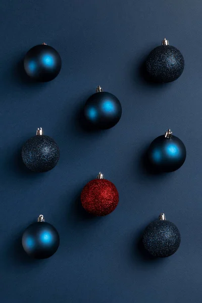Christmas card with blue balls and one unique red ball on dark blue background