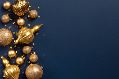 Altın parıltılı topları olan Noel çerçevesi ve mavi arka planda fotokopi alanı olan oyuncaklar