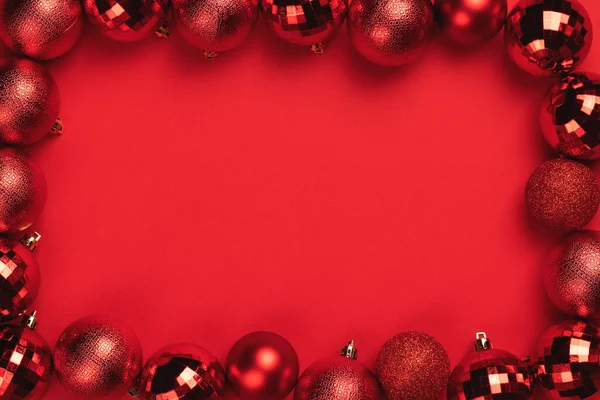 红色圣诞彩球装饰在红色背景与复制空间 问候卡的框架 顶部视图 — 图库照片