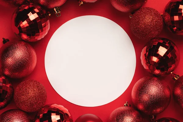Красные Рождественские Безделушки Украшения Вокруг Белого Пустого Круга Красном Фоне — стоковое фото