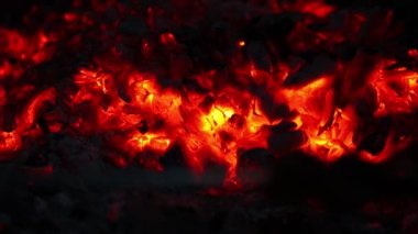 Kırmızı kömürleri yakın çekimde yakıyor. Sıcak kömür karanlıkta parıldıyor ve parlıyor..
