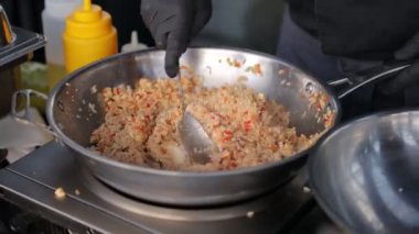 Aşçı tavada sebzeli ve baharatlı pilav hazırlar..