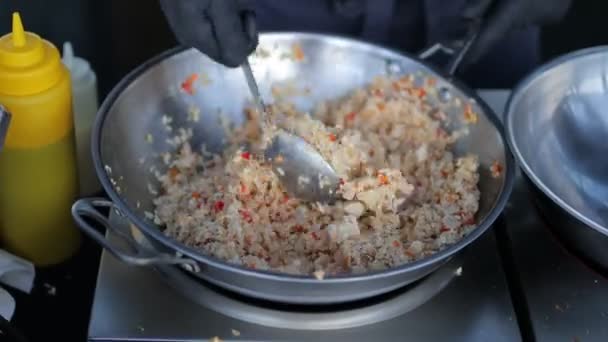 Kok bereidt rijst met groenten en specerijen in een wok. — Stockvideo