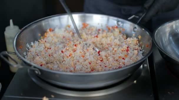 Kok bereidt rijst met groenten en specerijen in een wok. — Stockvideo