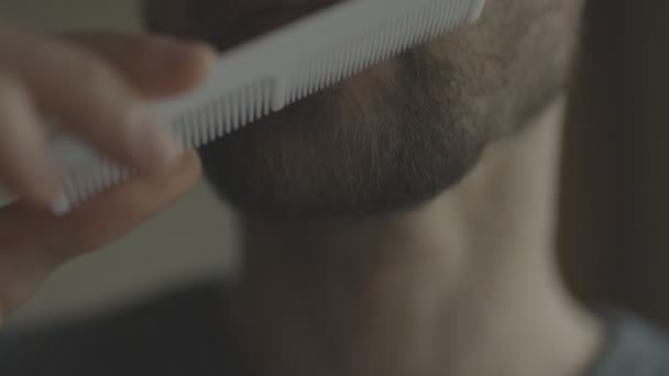 Ein Mann kämmt seinen Bart mit einem weißen Kamm. — Stockvideo