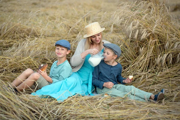 ママは彼女の息子に小麦畑でロールとシップスミルクを与えます — ストック写真