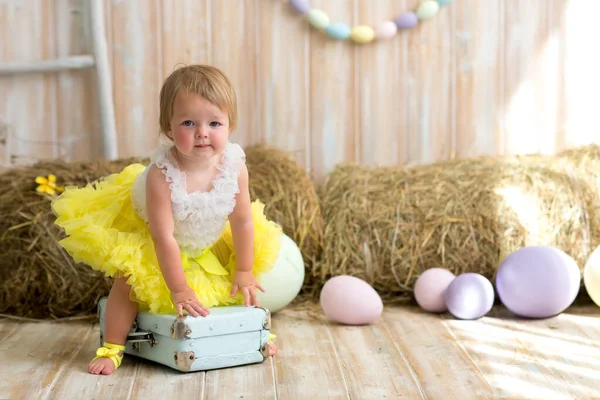 黄色のスカートの絵の卵の横に座って陽気少女 イースター休暇中の子供の概念 — ストック写真