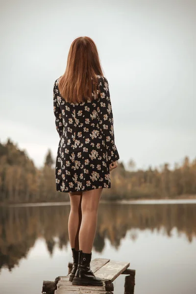 Orman gölünün arka planında tahta bir köprüde duran bir kız.. Stok Fotoğraf