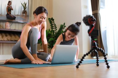 Helathy ailesi annesi ve kiz kiz laptopla internetteki egitimle yoga yapiyor.