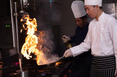 Chelf ve yardımcıları mutfakta yemek pişiriyor, şef bir restoranın mutfağında yemek hazırlıyordu.