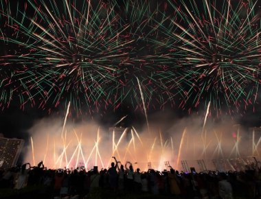 Crowd of tourists celebrating New Year looking at beautiful firework show