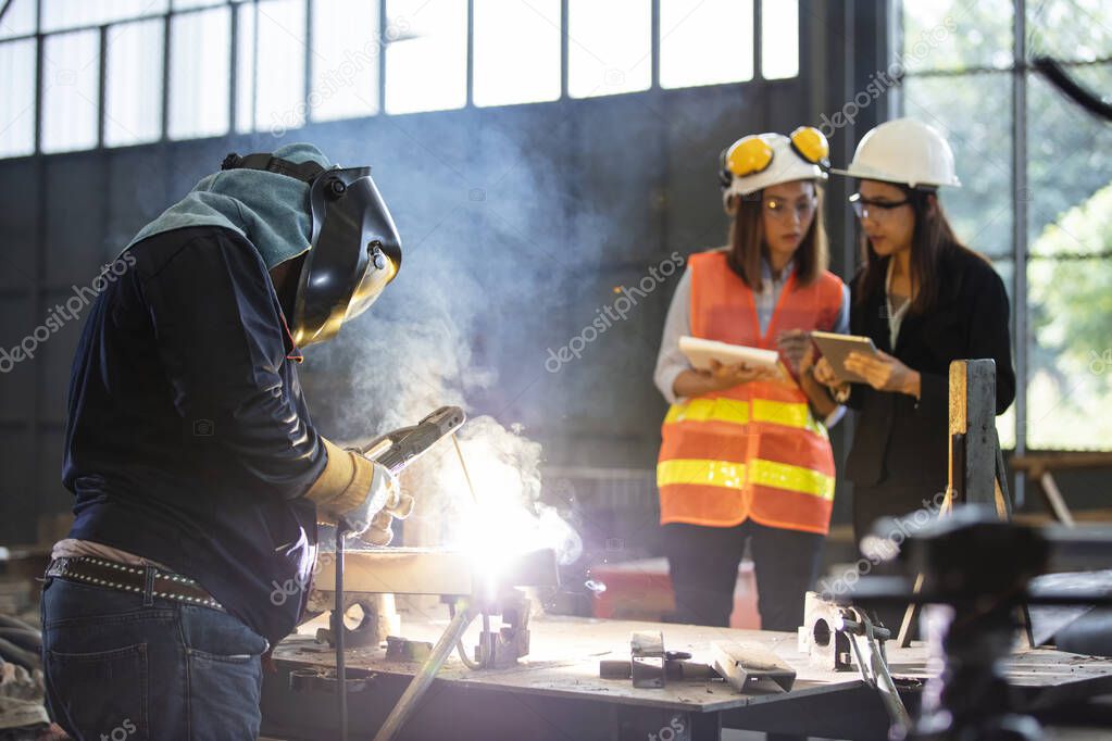 Two Business women discussing an working front welding production process.  Quality audit and process walk in manufacturing 