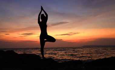 Siluet Genç kadın gün batımında Rod sahilinde Yoga, Slim ve Sağlıklı kadın egzersizi güneş batımında gökyüzüne karşı, dışarıda sağlık yaşam tarzı