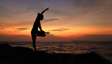Siluet Genç kadın gün batımında Rod sahilinde Yoga, Slim ve Sağlıklı kadın egzersizi güneş batımında gökyüzüne karşı, dışarıda sağlık yaşam tarzı