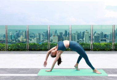 Asyalı kadın Bangkok Tayland 'daki gökdelen çatısında temel Yoga egzersizi yapıyor. 