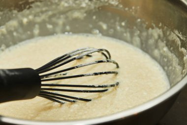 Yoğurtlanmış hamuru metal kasede çırp..