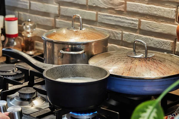 Preparing food in frying pan and casseroles on the gas stove in the kitchen. Home cooking concept.