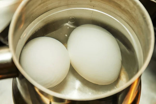 Chicken eggs are boiled in saucepan on gas stove — Stock Photo, Image