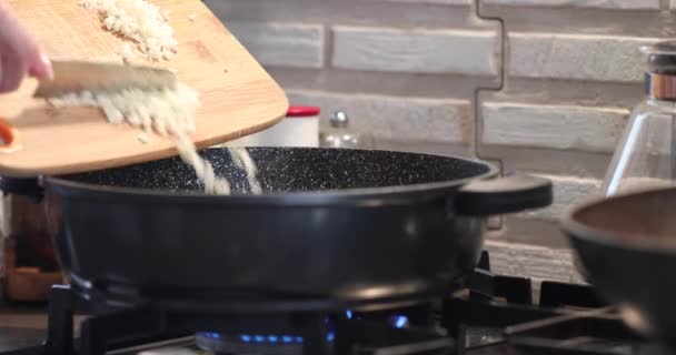 A szakács hagymát önt a serpenyőbe a tűzre. — Stock videók