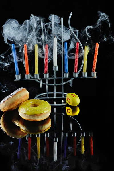 Hanukkah feliz e Hanukkah Sameach - castiçal judaico tradicional com velas ardentes e rosquinhas contra fundo preto com reflexão. — Fotografia de Stock