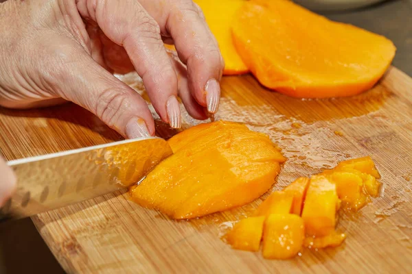 Cook cuts juicy mango into slices for making salad — Stock Photo, Image
