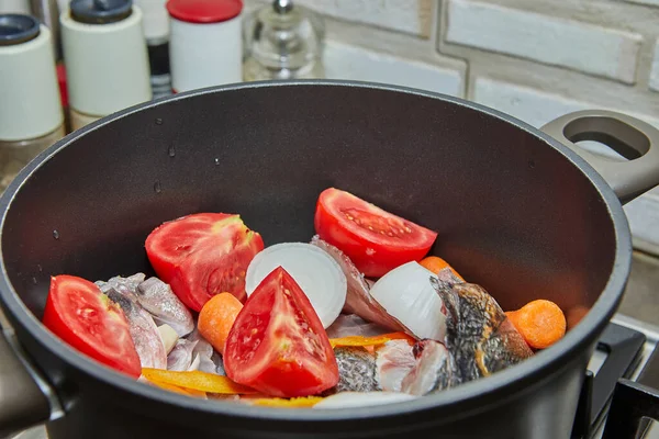 Рыбный окунь варят в котле с помидорами, морковью и луком на газовой плите — стоковое фото