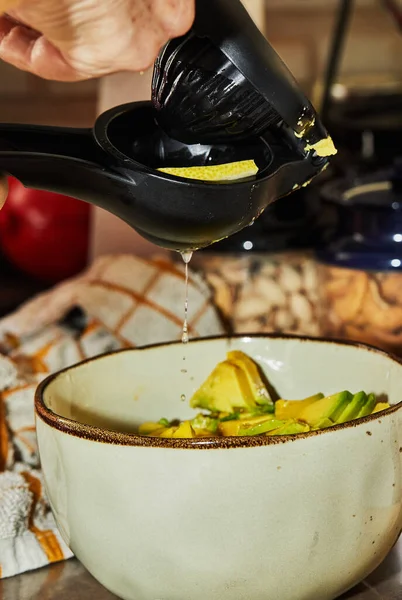 Aşçı salataya limon suyu sıkıyor. Salata hazırlamak için özel bir cihaz kullanıyor.