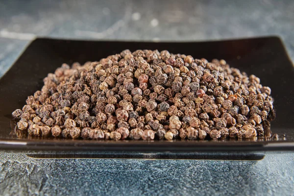 Brown Peppercorns Black Plate Reflection — стоковое фото