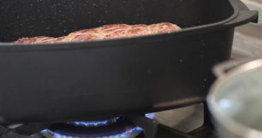 Biftek, gaz sobasında kazanda kızarır ve yağ ile ıslanır.
