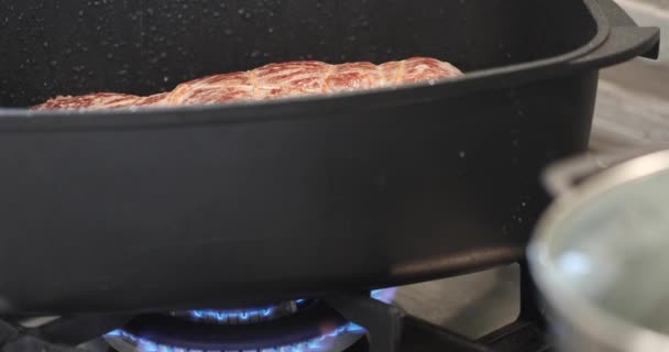Говядина жарится в котле на газовой плите и брызгает маслом — стоковое видео