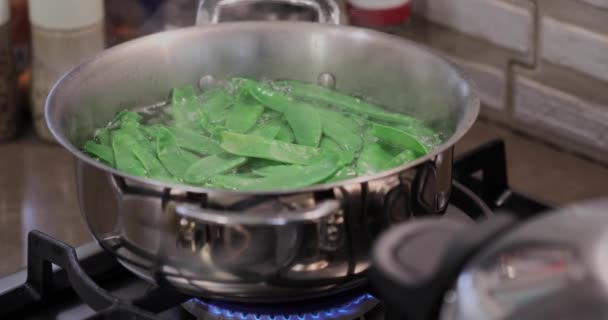 Groene erwten worden gekookt in steelpan op het gasfornuis — Stockvideo
