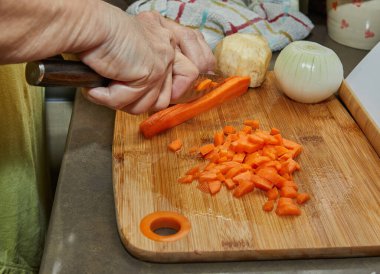 İnternetteki tariflere göre kadın ev yemeği için havuç kesiyor. Pişirmeden önce malzemeleri ve sebzeleri hazırlayın.