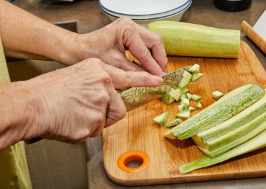 Kadın internette tarifi kullanarak evde yemek pişirmek için kabak kesiyor.