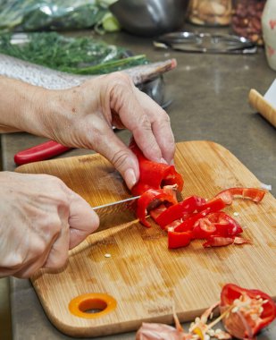 İnternetteki tarifi kullanarak evde yemek pişirmek için kırmızı biber kesiyor.